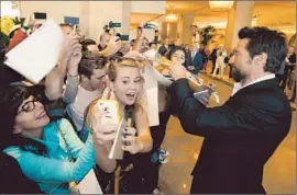  ?? Al Seib
Los Angeles Times ?? HUGH JACKMAN, right, signs autographs while fans take photos at the 85th Academy Awards nominees luncheon at the Beverly Hilton Hotel last year.