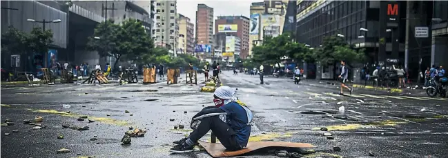  ?? [ AFP ] ?? Die Antiregier­ungsprotes­te dauern an und könnten sich bis zum Wochenende weiter zuspitzen: Ein Jugendlich­er beteiligt sich an einer Straßenblo­ckade in Caracas.