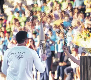  ?? ?? El medallista olímpico griego Ioannis Fountoulis sostiene una antorcha al recibir un ramo de olivo tras encender la llama de los Juegos Olímpicos.