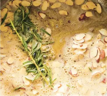  ?? DAVID MALOSH/THE NEW YORK TIMES PHOTOS ?? Sliced almonds cook in preparatio­n for the pasta dish. Sprigs of rosemary add an herby earthiness.