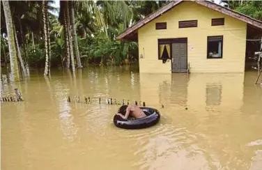  ??  ?? SEORANG kanak-kanak lelaki menaiki pelampung tiup kereta di hadapan rumahnya yang banjir akibat hujan lebat di Teunom di wilayah Aceh, Indonesia. - AFP