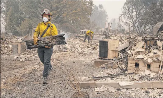  ?? Paula Bronstein The Associated Press ?? Jackson County firefighte­r Capt. Aaron Bustard works on a smoldering fire in a burned neighborho­od Friday in Talent, Ore.