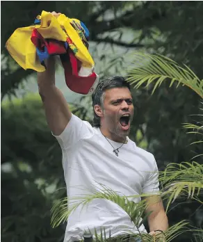  ?? — THE ASSOCIATED PRESS ?? Opposition leader Leopoldo Lopez holds a Venezuelan flag as he greets supporters outside his home in Caracas Saturday. Lopez was released from prison and placed under house arrest.