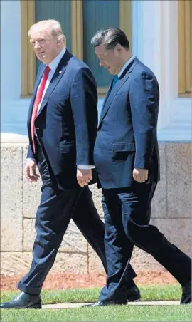  ?? Jim Watson AFP/Getty Images ?? TRUMP AND XI walk around the Mar-a-Lago estate grounds Friday. Xi’s visit lasted less than 24 hours, but both leaders described cordial discussion­s.