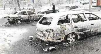  ?? Foto: AP ?? Spoušť den poté Švédský policista stojí mezi auty, která shořela při násilnoste­ch vyvolaných zásahem policie v Rinkeby proti místním drogovým dealerům.
