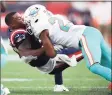  ?? Adam Glanzman / Getty Images ?? Patriots running back Damien Harris is tackled by the Dolphins’ Byron Jones during the first half on Sunday in Foxborough, Mass.