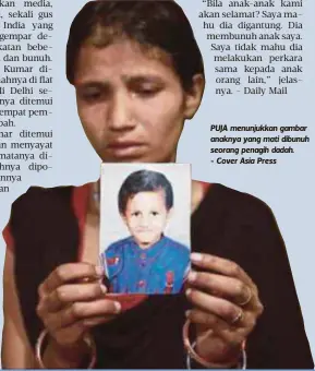  ??  ?? PUJA menunjukka­n gambar anaknya yang mati dibunuh seorang penagih dadah. - Cover Asia Press