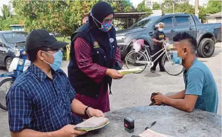  ?? BERNAMA PIC ?? Terengganu Health director Dr Nor Azimi Yunus (centre) issuing a compound to a patron for failing to register and check his temperatur­e at an eatery in Kuala Terengganu yesterday.