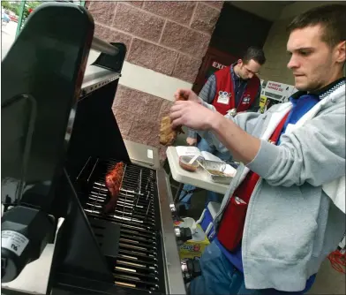  ?? MEDIANEWS GROUP FILE PHOTO ?? Lowes Customer Service Associate Brandon Wittmann (cq) places a rack of ribs on the Jenn-Air 44,000Btu Gas Grill after converting it from a Rotisserie Grill to a convention­al grill.