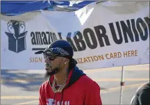  ?? AP ?? Chris Smalls, president of the Amazon Labor Union, stands by an informatio­n booth collecting signatures across the street from an Amazon distributi­on center in New York on Thursday.