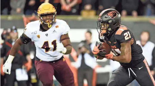  ?? AP ?? Oregon State running back Artavis Pierce runs with the ball as Arizona State defensive lineman Tyler Johnson closes in.