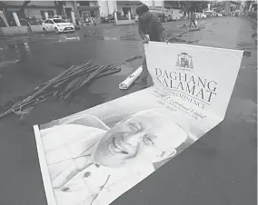  ??  ?? THANK YOU — A man rolls out a tarpaulin of a smiling late Cebu Archbishop Emeritus Ricardo Cardinal Vidal with a message of thanks. The tarpaulin will be among the many which will hang along the route of the funeral procession tomorrow, October26....