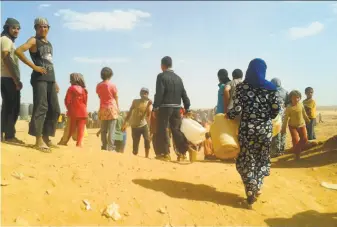  ?? Associated Press 2016 ?? Syrian refugees gathered for water last year at the Rukban camp between the Jordan and Syrian borders. Only sporadic aid shipments have reached Rukban and a second remote desert camp.