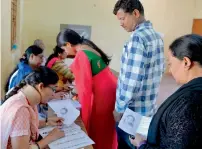  ??  ?? People queue up to cast their ballots and, right, ex-cricket captain Anil Kumble and his family show ink-marked fingers in bengaluru. —