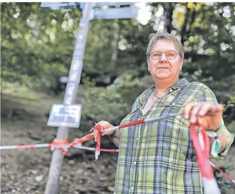  ?? FOTO: STEPHAN KÖHLEN ?? Instandset­zung des Weges hinter dem Steinzeits­pielplatz: Biologin Ursula Ripke macht auf Erosionen entlang der Düssel aufmerksam. Diese Bereiche sind mit Flatterbän­dern abgetrennt.