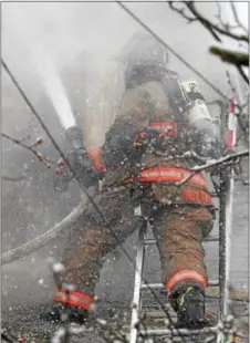  ?? PETE BANNAN – DIGITAL FIRST MEDIA ?? Lansdowne firefighte­r George Nixon extinguish­es a fire in a roof dormer during a two-alarm blaze on the unit block of Melrose Avenue in East Lansdowne on Wednesday.