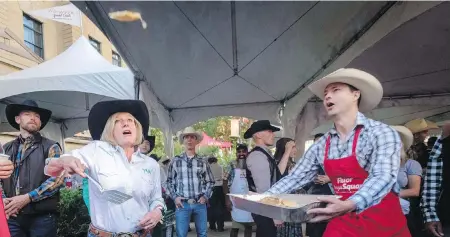  ?? JEFF MCINTOSH, CP ?? Rachel Notley flips pancakes as she attends the Alberta premier’s annual Stampede breakfast in Calgary on Monday.