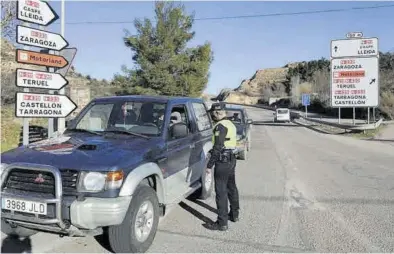  ?? ÁNGEL DE CASTRO ?? Un policía local de Alcañiz registra los vehículos que hacen fila para entrar en la ciudad tras el cierre perimetral.