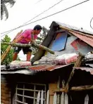  ?? —MICHAEL B. JAUCIAN AND MARK ALVIC ESPLANA ?? IN TYPHOON’S PATH A man in Ligao City, Albay province, reinforces the roof of his house (left photo) while residents in Santo Domingo town take shelter in a school as the Bicol region braces itself for Typhoon “Tisoy” on Monday.