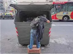  ?? — AFP ?? BUENOS AIRES: A man rummages through a garbage bin in Buenos Aires.