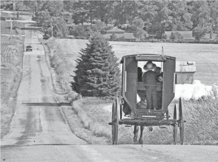  ?? MIKE SCHENK/THE-DAILY-RECORD.COM ?? An Amish buggy is loaded as it makes its way down a hill near Apple Creek.