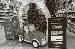  ?? David Zalubowski / Associated Press ?? A mailbox for letters to Santa stands with a Christmas display next to a sign encouragin­g social distancing in a Lowe’s store Friday in Northglenn, Colo. Retailers want to avoid Black Friday-type crowds as COVID-19 cases spike.