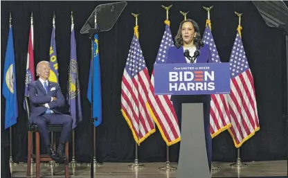  ??  ?? ABOVE: Former Vice President Joe Biden listens as his running mate, Sen. Kamala Harris, speaks at Alexis Dupont High School in Wilmington, Delaware, Wednesday.