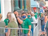  ?? AP PHOTO/RUSS BYNUM ?? St. Patrick’s Day revelers in masks wait in line outside to get into a bar in Savannah, Ga., on March 17.