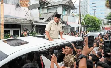  ?? AP ?? Big burden: Prabowo greets supporters in Jakarta. The presidenti­al frontrunne­r has pledged social assistance programmes totalling 460 trillion rupiah. —