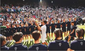  ?? AFP ?? ■ Serbia’s Novak Djokovic holds the winner’s trophy as he leaves the centre court at the All England Lawn Tennis Club in Wimbledon on Sunday.