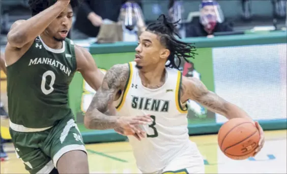  ?? James Franco / Special to the Times Union ?? Siena senior Manny Camper drives to the basket against Manhattan junior Warren Williams during a Metro Atlantic Athletic Conference game at UHY Center on the Siena campus in Loudonvill­e on Friday. Camper, a MAAC Player of the Year candidate, finished with 14 points and six rebounds.