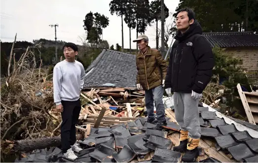  ?? The Yomiuri Shimbun ?? Shingo Koie, right, looks at the landscape changed by the earthquake as he visits his destroyed home in Suzu, Ishikawa Prefecture, on March 28.