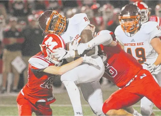  ?? | JEAN LACHAT/ FOR THE SUN- TIMES ?? Brother Rice’s Dale Williams is brought down by Marist’s Jimmy Porter ( left) and Danny Meehan on Friday night at Marist in Chicago.