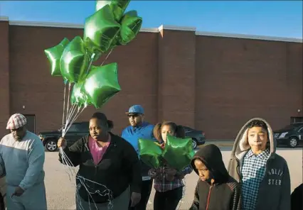  ?? Stephanie Strasburg/Post-Gazette ?? Cynthia Marshman, 27, carries balloons to the parking space where her nephew, 16-year-old Deven Holloway, was shot and killed outside Linton Middle School after a vigil for him at the school on Wednesday in Penn Hills. The sophomore at Penn Hills High...