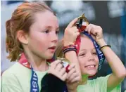  ?? Jason Fochtman ?? Isabella Fitzsulliv­an, right, celebrates with her new medal after finishing the annual 10 for Texas race on Saturday.