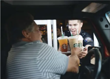  ?? PHOTO ?? Calexico Police Officer Jorge Ruiz serves coffee to a drive-thru customer at Starbucks during the police department's Coffee With A Cop event in Calexico on Tuesday evening. VINCENT OSUNA