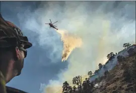  ?? Allen J. Schaben Los Angeles Times ?? CAPT. TOM LAWSON of the Los Angeles County Fire Department watches a helicopter drop water on the Bobcat f ire Sunday in the Angeles National Forest.