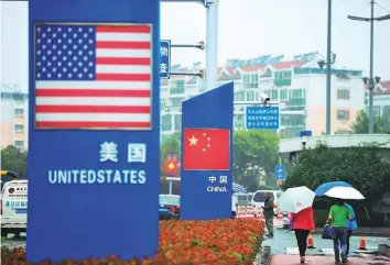  ?? AFP ?? Signs with the US and Chinese flags are seen outside a store selling imported goods in Qingdao, China. Beijing has yet to publicly accept a US invitation extended last week to hold talks.