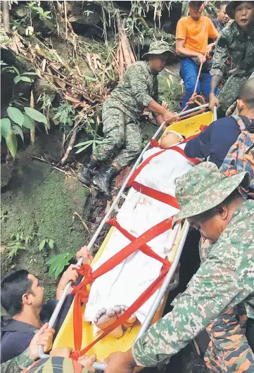  ??  ?? Rescuers in the process of moving Kho to the foot of the mountain.