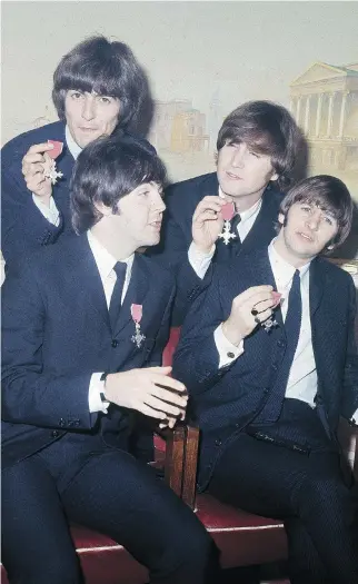  ?? THE ASSOCIATED PRESS ?? George Harrison, left, Paul McCartney, John Lennon and Ringo Starr display their medals after being invested as members of the Order of the British Empire at Buckingham Palace in 1965.