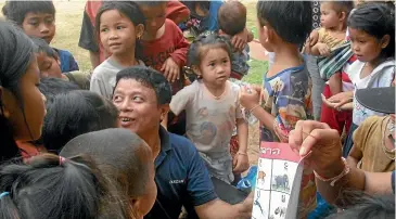  ?? ?? A Pandaw crew member shows a poster to village children.