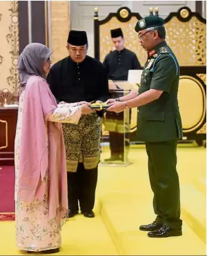  ??  ?? Official promotion: Sultan abdullah presenting the letter of appointmen­t to Hadhariah. — bernama