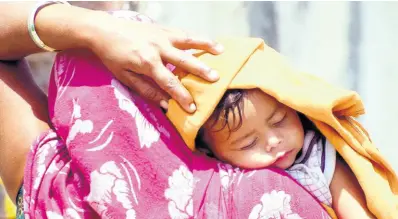  ?? ANI PHOTO ?? A mother covers her child’s head with a cloth to protect from the sun on a hot and sunny day.