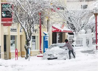  ??  ?? A driver digs out of the snow on Fisgard Street on Tuesday. The sun is expected to shine and temperatur­es are forecast to rise today to 3 C.