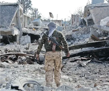  ?? JAKE SIMKIN/ THE ASSOCIATED PRESS ?? A Kurdish fighter moves down a ruined street in Kobani, Syria, site of heavy fighting against Islamic State.