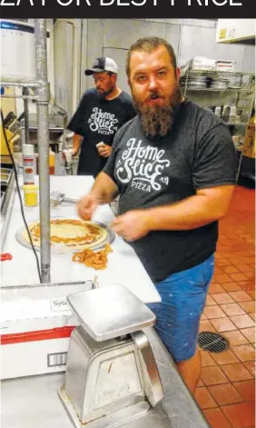  ?? STAFF PHOTO BY TIM OMARZU ?? Josiah Johnson, front, makes a pizza in the kitchen at Home Slice Pizza next to restaurant employee Sam Davis.