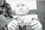  ?? BERND THISSEN/DPA VIA AP ?? Auschwit z sur vivor Leon Schwarzbau­m, 94, shows a photograph of himself (lef t) nex t to his uncle and parent s who all died at the camp. Today, Schwarzbau­m will testif y against Reinhold Hanning, a 94-year-old former SS guard at Auschwit z.