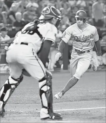  ?? Norm Hall Getty Images ?? TIM LOCASTRO scores the tying run on a single by pinch-hitter Max Muncy during the seventh at Arizona. They scored twice in the inning to take the lead and cut their magic number to clinch the NL West to five.