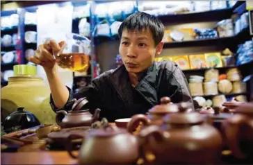  ?? SHIHO FUKADA/THE NEW YORK TIMES ?? Wang Rouyu, a longtime tea dealer, serves Pu’er tea in his shop in Jinghong, China, on December 22, 2009.