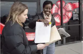  ?? CHRISTINE T. NGUYEN AP ?? Mary Blitzer, of the Sierra Club, gives a petition of over 23,000 signatures to Amira Adawe of the Beautywell Project as they deliver it to the Amazon Fulfillmen­t Center in Shakopee, Minnesota on Wednesday. The two non-profit groups launched a campaign for Amazon and E-bay to stop selling toxic skin-lightening creams that contain mercury.